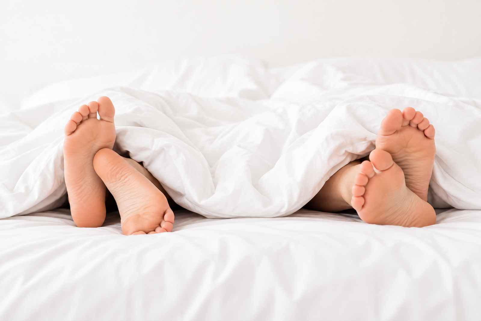 Stopy dwojga ludzi pod biala koldra